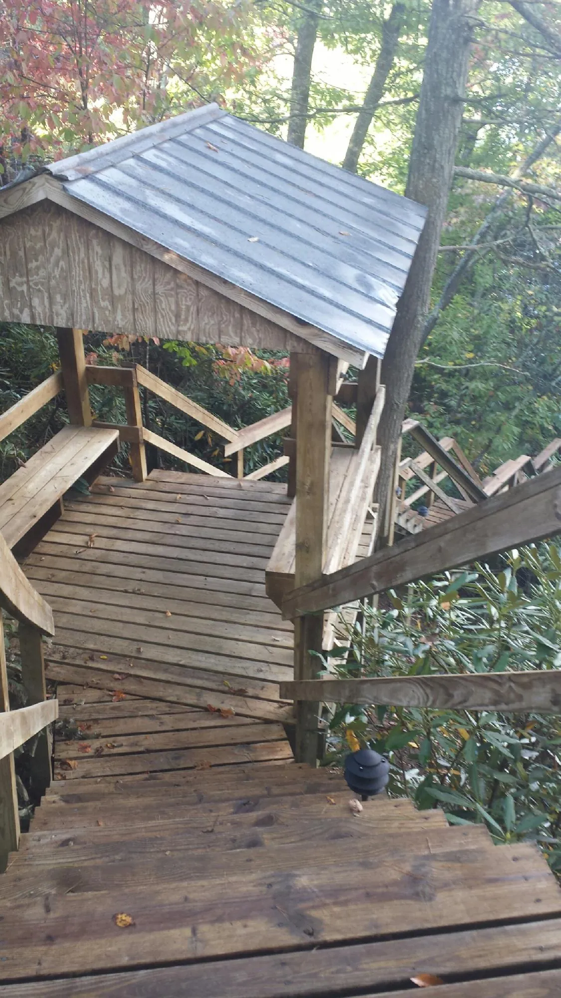 Metal roofed shelter over wooden steps on a wooded walkway — Skylight Repair & Installation work by our crew in Knoxville