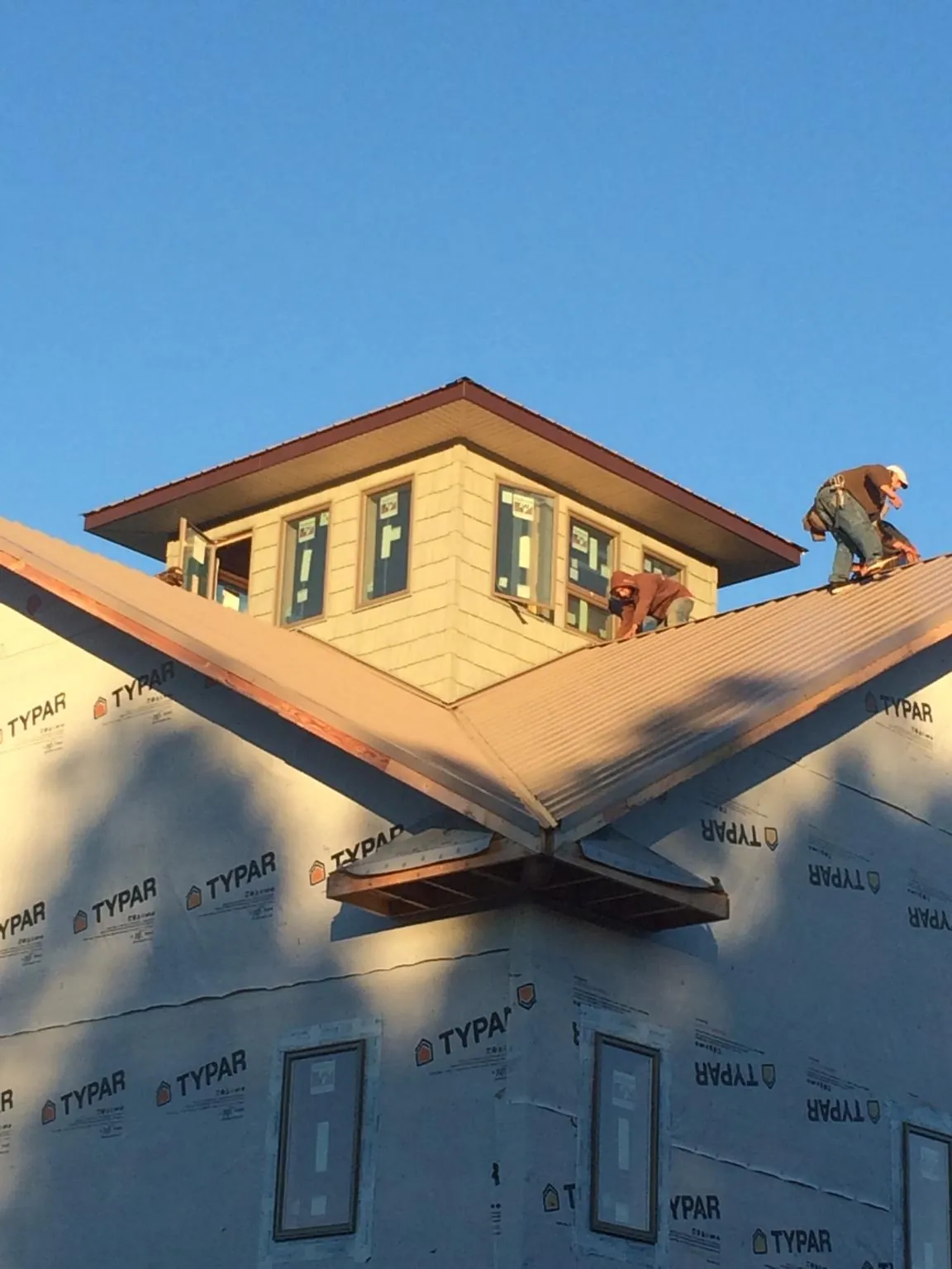 Roofers working around a rooftop cupola on a new metal roof at sunset — Roof Waterproofing in Knoxville by Roofing Brothers